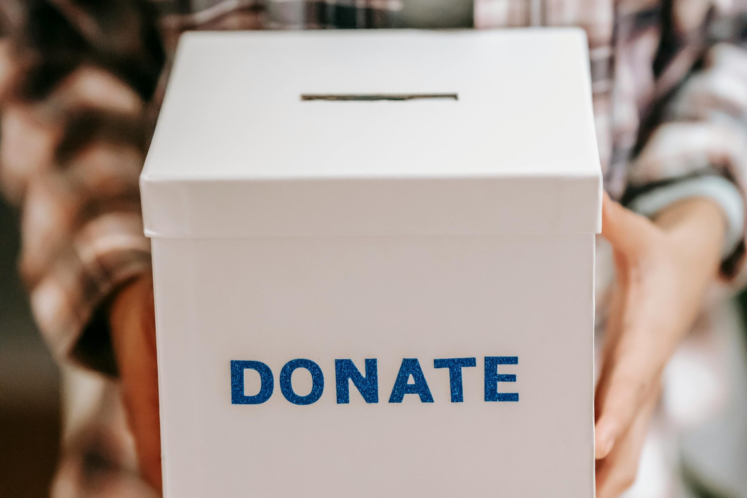 Crop anonymous person showing donation box